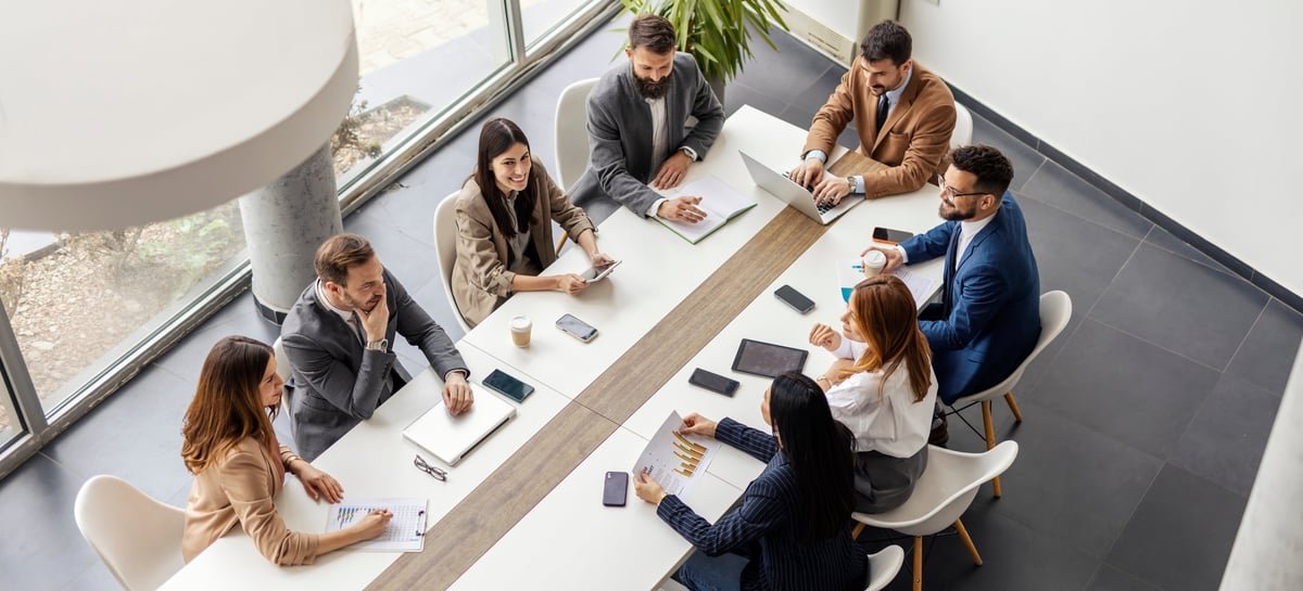 From above view of leadership team sitting and conference table at boardroom and having meeting
